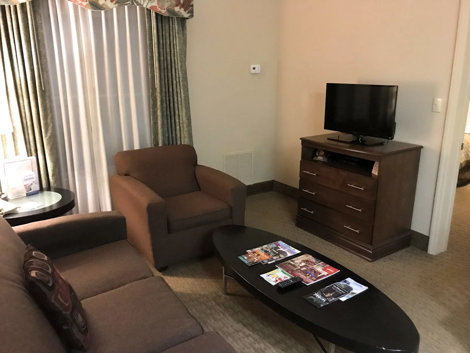 sitting area in the room, brown couches, black tables and tv