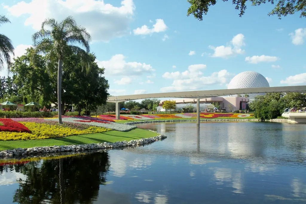 waterway outside of epcot with the spaceship earth geosphere in the back ground and the monorail track in the foreground