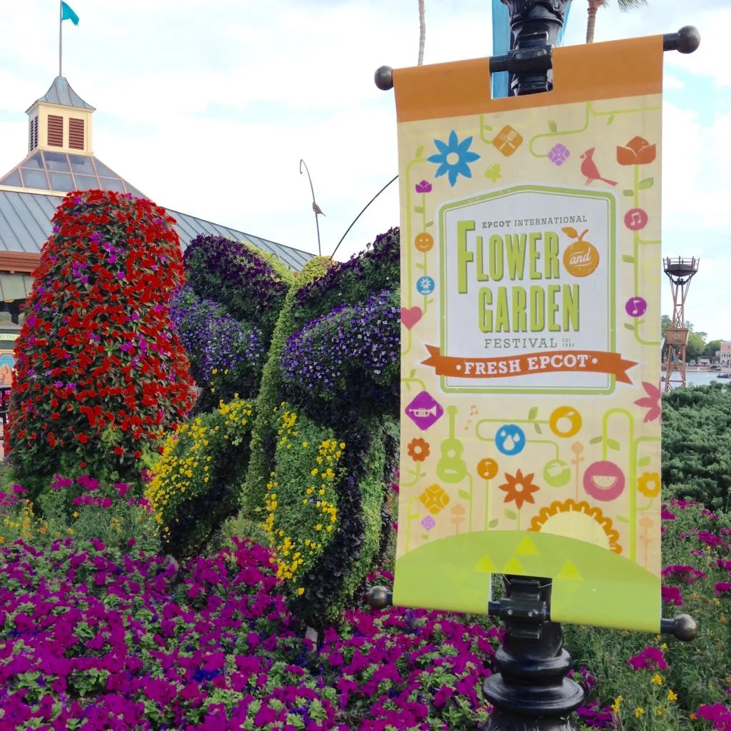 flower and garden festival sign in front of a a butterfly made out of plants and flowers