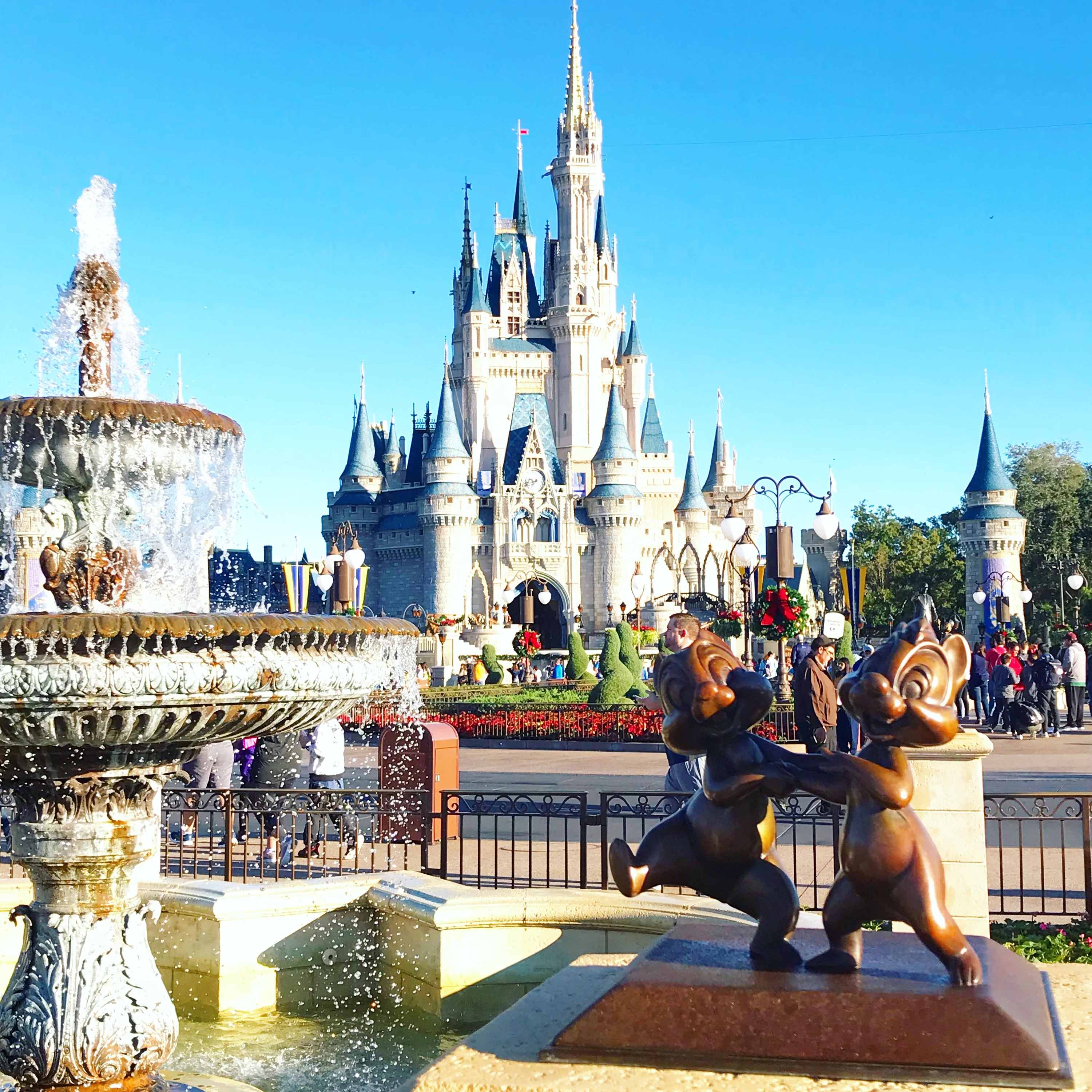 chil and dale statue next to fountain with cinderella's castle in the background