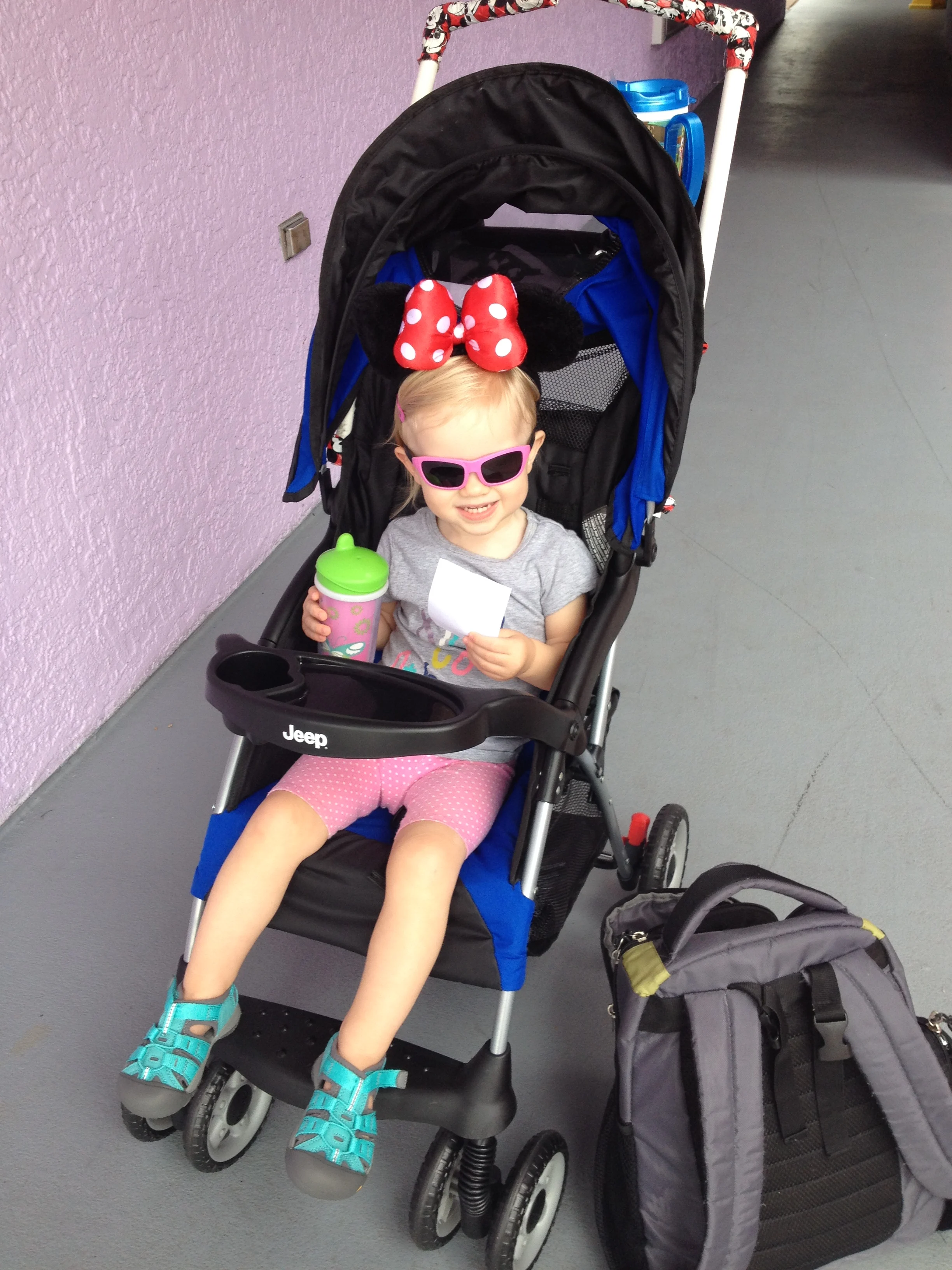 little girl sitting in a stroller with minnie mouse ears