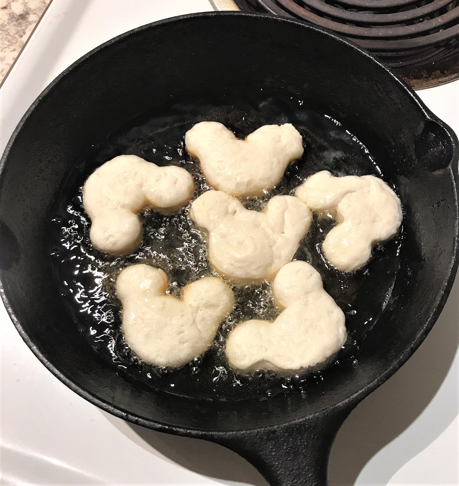mickey beignets frying in cast iron skillet